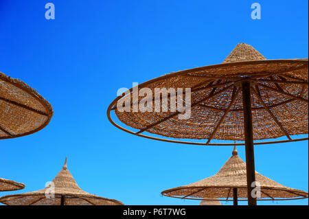 Sonne - Schutz wicker Sonnenschirme am Strand gegen den Himmel, das Konzept der Sommer Tourismus Stockfoto