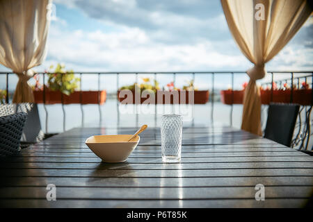 Einen leeren Teller und ein leeres Glas auf einen hölzernen Tisch in einem Cafe. Stockfoto