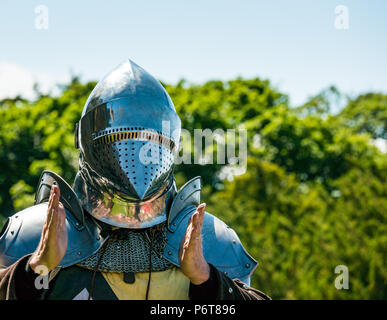 Mann in mittelalterlichen Rüstung und Knight's Helm im Sprechen über mittelalterliche Waffen von Historic Scotland, dirleton Castle, East Lothian, Schottland, Großbritannien Stockfoto