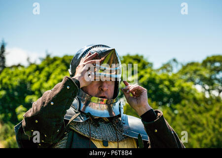 Andrew Spratt in mittelalterlichen Rüstungen und Knight's Helm im Sprechen über mittelalterliche Waffen von Historic Scotland, dirleton Castle, East Lothian, Schottland, Großbritannien Stockfoto