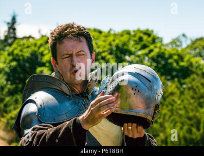 Andrew Spratt in mittelalterlichen Rüstungen und Knight's Helm im Sprechen über mittelalterliche Waffen von Historic Scotland, dirleton Castle, East Lothian, Schottland, Großbritannien Stockfoto