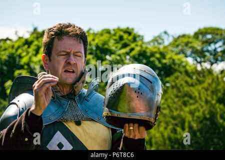 Andrew Spratt in mittelalterlichen Rüstungen und Knight's Helm im Sprechen über mittelalterliche Waffen von Historic Scotland, dirleton Castle, East Lothian, Schottland, Großbritannien Stockfoto