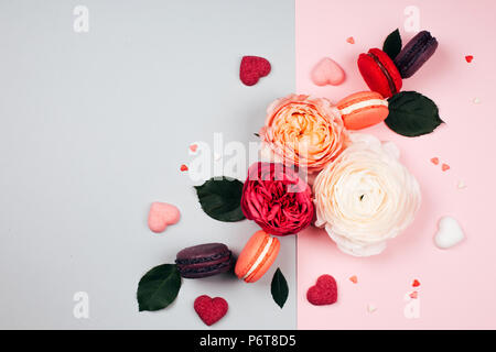 Zusammensetzung der Macarons und Blumen in grau und rosa Farben. Flach. Für Ihren Text. Stockfoto