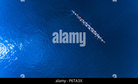 Zwanzig Mann im Boot lange Schwanz auf dem Meer. nach oben Blick auf Mann Paddeln Stockfoto