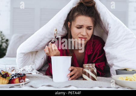 Betonte Frau essen Big Ice Cream und Weinen Stockfoto