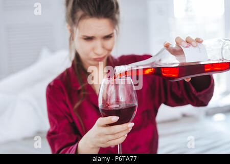 Emotionale Frau gießen Rotwein in ihr Glas Stockfoto