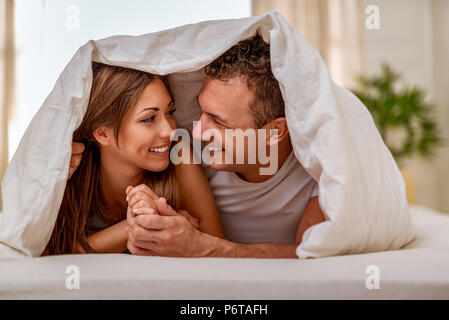 Schöne junge Liebende Paar einander mit Liebe und in ruhigen Morgen im Bett mit Decke abgedeckt. Stockfoto