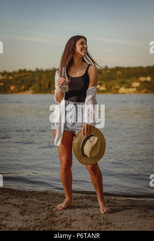 Portrait einer jungen lächelnde Frau mit Strohhut bei Sonnenuntergang erholsame Zeit am Ufer. Stockfoto