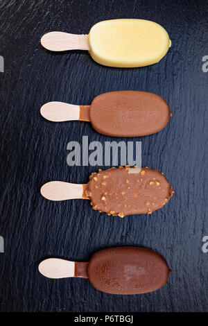 Eis auf Stick mit Schokolade auf schwarzen Stein Schiefer board abgedeckt. Stockfoto