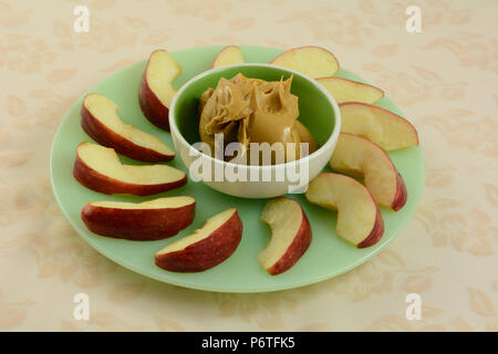 Apple Slices auf Grün snack Plate mit kleinen grünen Schüssel voll mit Erdnußbutter in Zentrum für Tauch Stockfoto