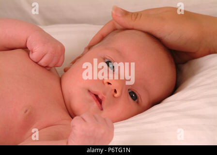 Mütter Hand streichelte den Kopf Ihres Babys Stockfoto