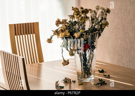 Vase mit toten Blumen auf einen Esstisch. Stockfoto