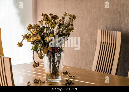 Vase mit toten Blumen auf einen Esstisch. Stockfoto