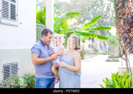 Glückliche Familie von drei - schwangere Mutter, Vater und Tochter umarmen, Lachen, Spaß in der Sunset Park. Familie Erholung, Zeit bereitgestellt Stockfoto