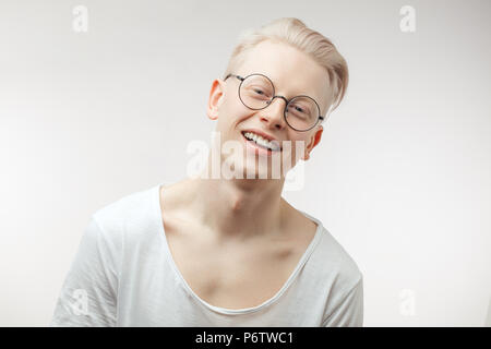 Gerne blonde Mann mit ungewöhnlichen stattliches Aussehen zufrieden lächelnd in die Kamera in Träumen Ausdruck mit kommenden Feiertage glücklich zu werden. Stockfoto