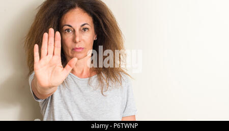 Gewelltes Haar Brasilianerin mit offener Hand das STOP-Schild mit ernsten und selbstbewussten Ausdruck, Verteidigung Geste Stockfoto