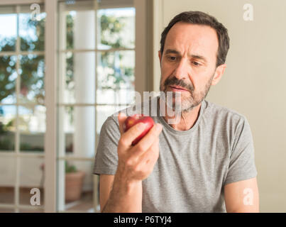 Mittleres Alter Mann gesund essen red apple mit einem selbstbewussten Ausdruck auf Smart Face denken Ernst Stockfoto