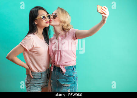 Portrait von ziemlich charmant Mädchen im casual Outfits schießen selfie auf der Vorderseite mit Smart Phone auf helle violette Hintergrund isoliert Kamera. Wochenende va Stockfoto