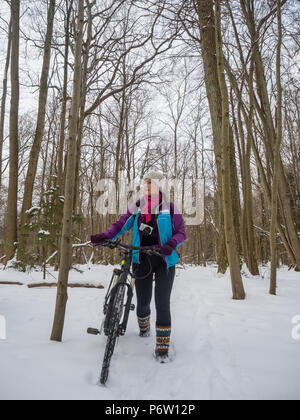 Mädchen mit einem Fahrrad, einem Radfahrer im Winter Wald Stockfoto