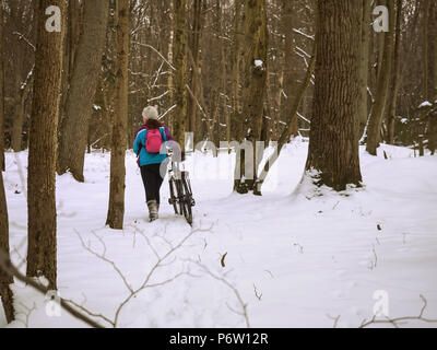 Mädchen mit einem Fahrrad, einem Radfahrer im Winter Wald Stockfoto