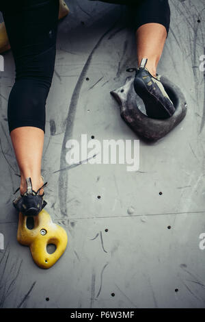 Unten in der Nähe der Kletterer weibliche Füße auf künstliche Kletterwand. Frau Fuß in der Kletterschuhe auf künstliche Haken Stockfoto
