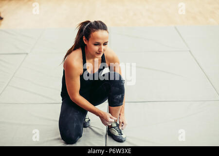 Sportliche Frau binden der Schnürsenkel auf Schuhen an der Kletterhalle vor dem Training. Stockfoto