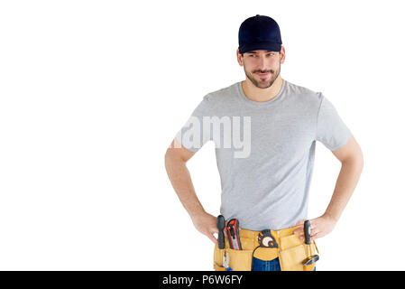 Portrait von hübscher junger Handwerker tragen Baseball Cap und Werkzeug Gürtel beim Stehen an vereinzelten weißen Hintergrund mit kopieren. Stockfoto