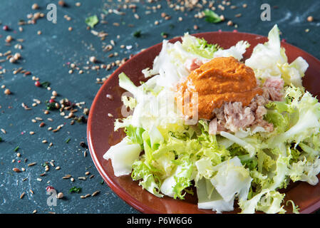 Escarola amb romesco, salatköpfe Endiviensalat mit romesco Sauce, eine typische Salat aus Katalonien, Spanien, auf braunem Steingut Teller, platziert auf einem rustikalen dunklen Stockfoto