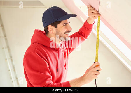 Porträt eines jungen Mannes mit Maßband während der Arbeit auf der Baustelle. Stockfoto