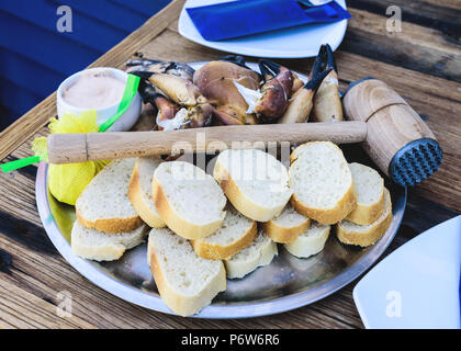 Platte mit gekochten Beine und Klauen von Braun Krabbe mit Brot und Dip auf hölzernen Tisch Stockfoto