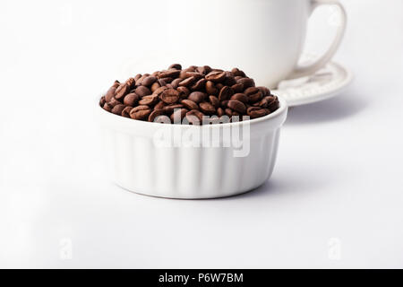 Kaffeebohnen in einer weißen Schüssel mit einer Tasse Kaffee auf weißem Hintergrund Stockfoto
