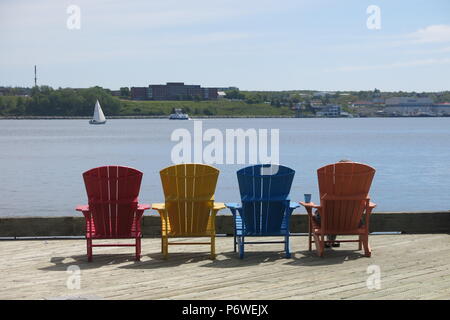 Vier bunten Adirondack Stühlen zu sitzen und den Blick über die Uferpromenade in Halifax, Nova Scotia. Stockfoto