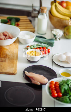 Frisches Bio-Gemüse und bunte Zutat zum Kochen gesunde Mahlzeit auf weißem Schreibtisch Hintergrund. Tomaten, Kopfsalat, Mais, Eier, Geflügelfleisch und oth Stockfoto