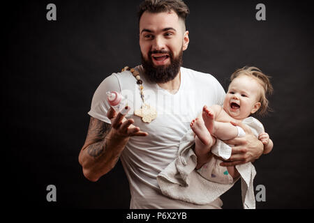 Parenting und liebe Konzept. Vater halten und die Pflege von kleinen Kind ein Jahr alten Baby, Füttern oder Tränken von der Krankenpflege Flasche. Stockfoto