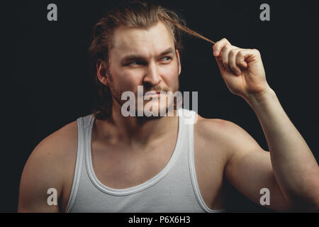 Junger Mann zieht sein Haar im Studio. close-up Portrait Stockfoto