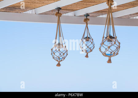 Stroh das Dach einer Terrasse oder Veranda mit hanging lantern und blauen Himmel sehen. viele Glühbirnen mit Seilen eingerichtet, Net an die Decke des Restaurant Stockfoto