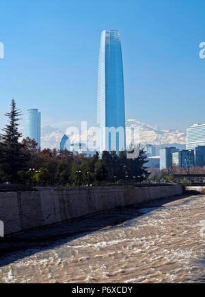 Chile, Santiago, Blick über Mapocho Fluss in Richtung die hohe Gebäude mit Costanera Center Tower, dem höchsten Gebäude in Südamerika. Schneebedeckten Anden im Hintergrund. Stockfoto