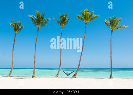 Juanillo Strand (Playa Juanillo), Punta Cana, Dominikanische Republik. Entspannen Sie sich auf einer Hängematte an einem palmengesäumten Strand (MR) Frau. Stockfoto