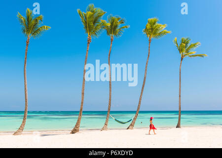 Juanillo Beach (playa Juanillo), Punta Cana, Dominikanische Republik. Frau, die zu Fuß auf einem Palmen-gesäumten Strand (MR). Stockfoto