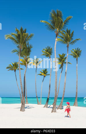 Juanillo Beach (playa Juanillo), Punta Cana, Dominikanische Republik. Frau, die zu Fuß auf einem Palmen-gesäumten Strand (MR). Stockfoto