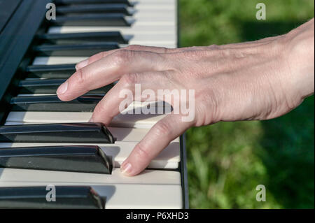 Eine Frau ist das Klavierspiel. Weibliche Hand auf die Klaviertasten. Sonnenlicht. Stockfoto