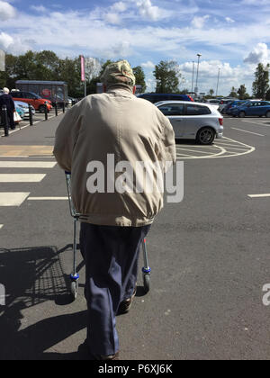 Ansicht der Rückseite des älteren Mannes schieben Einkaufswagen im Supermarkt Parkplatz Stockfoto