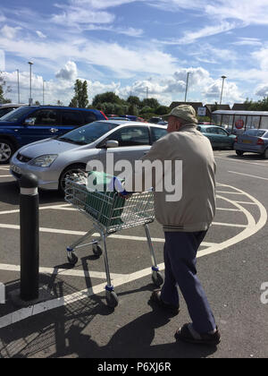 Ansicht der Rückseite des älteren Mannes schieben Einkaufswagen im Supermarkt Parkplatz Stockfoto