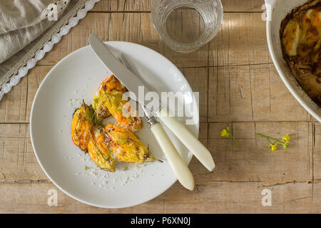 Mit Ricotta und Käse Gebackene Zucchini und Kürbis Blumen mit einem Glas Mineralwasser serviert gefüllt. Rutik Stil. Stockfoto