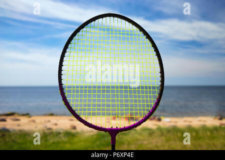 Schläger für Badminton spielen gegen das blaue Meer und den Horizont mit dem Strand Stockfoto