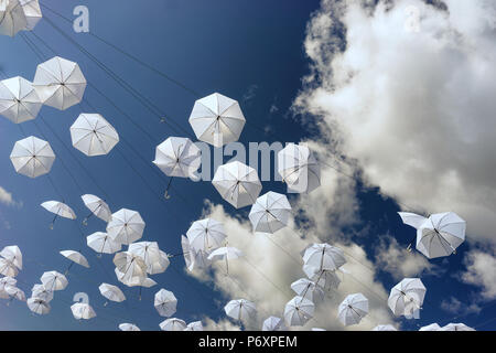 Weißer Schirme gegen einen blauen Sommerhimmel mit Wolken Stockfoto