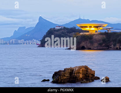 Brasilien, Bundesstaat Rio de Janeiro, Niteroi, Dämmerung Blick auf die niteroi Museum für Zeitgenössische Kunst mit Skyline von Rio de Janeiro im Hintergrund. Stockfoto