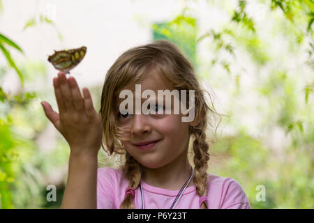 Blonde Mädchen mit einem gelben beschmutzt Schmetterling ion Fingerspitzen. Low Angle View. Selektive konzentrieren. Close Up. Stockfoto