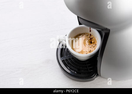 Kaffeemaschine füllt eine Tasse Kaffee auf Tisch Stockfoto