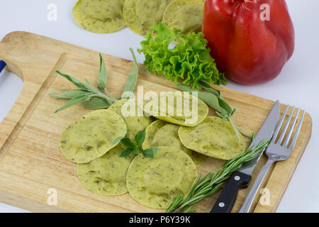 Italienische Pasta Ravioli mit grünem Kraut auf weißen Hintergrund/hausgemachte Pasta und Ravioli aus Holz mit Vintage Tasse Mehl und frischem Basilikum/Frisches p Stockfoto